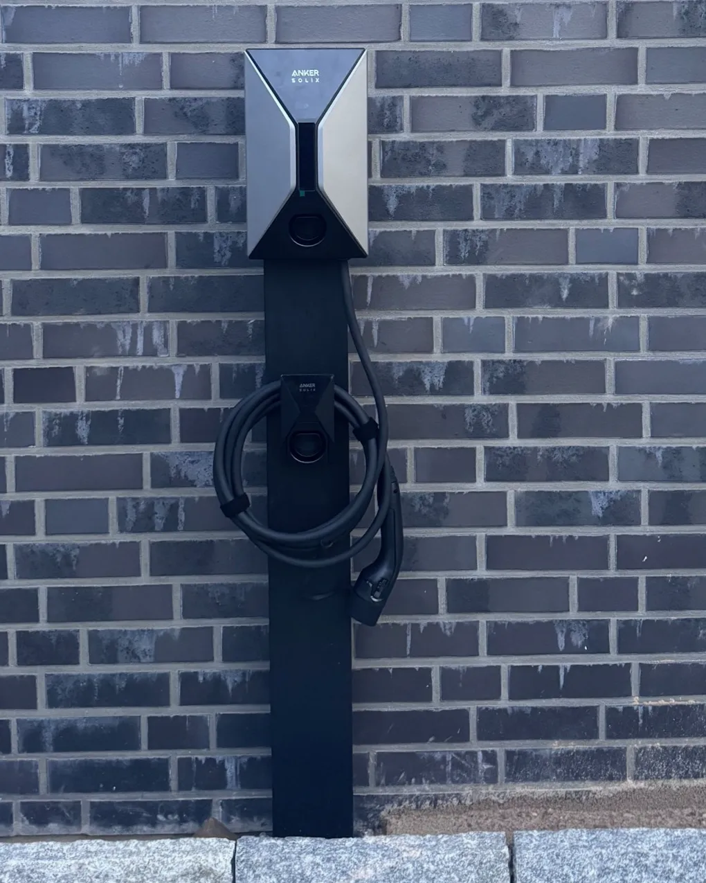 Fertig montierte Wallbox auf einer Standsäule vor einer Klinkerwand