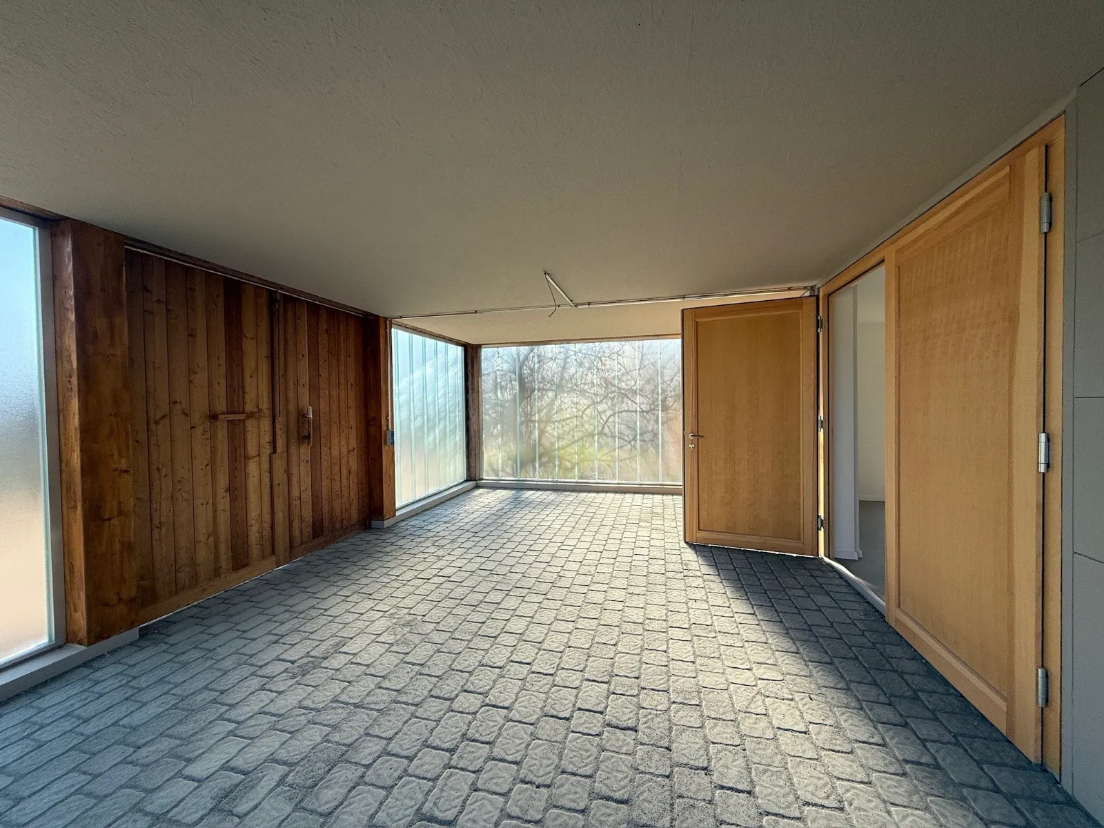 Helle Werkstatthalle mit Pflasterboden, Holzwänden und Glasbausteinfenstern